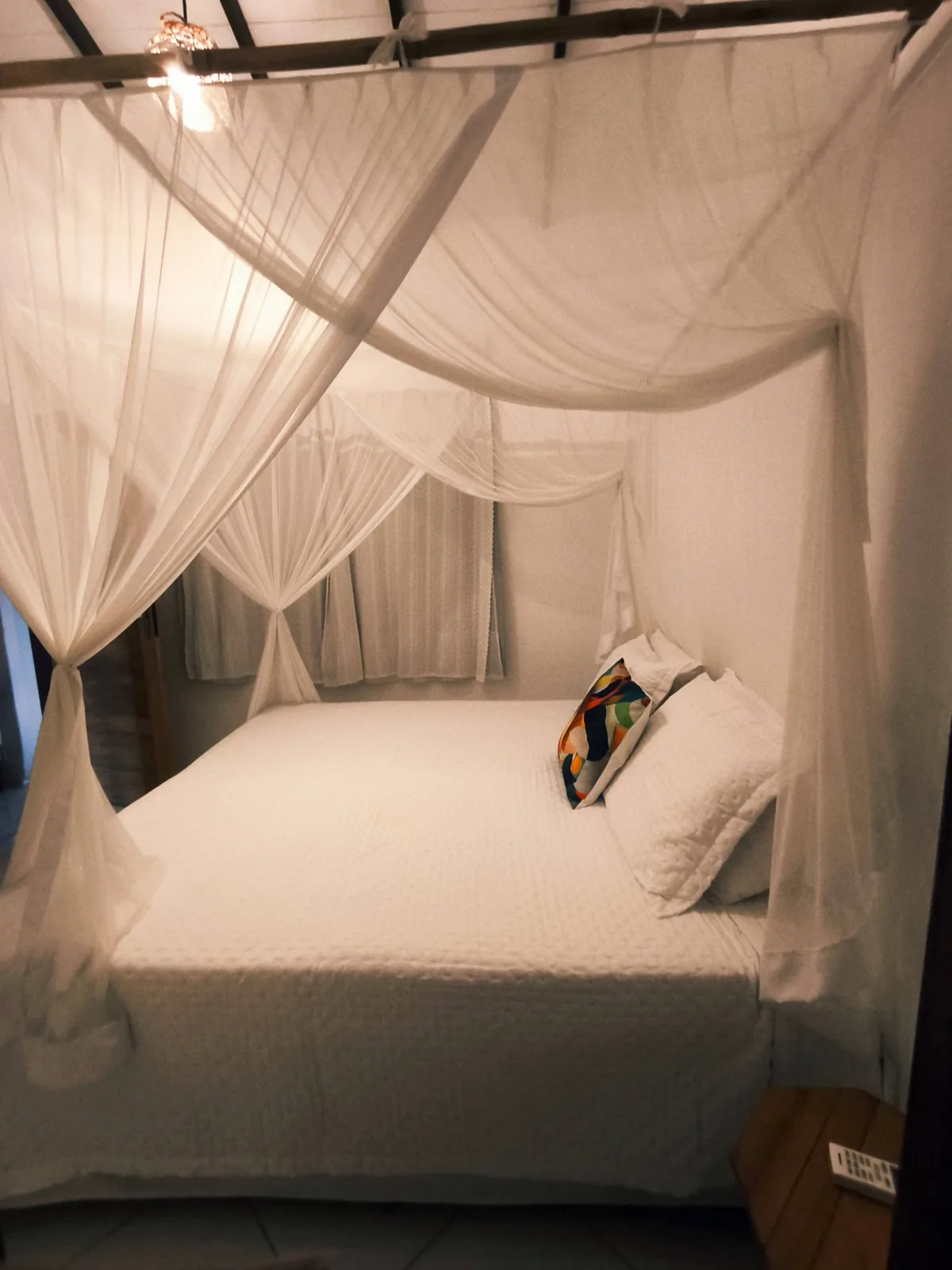 Suíte com cama king size e dossel de mosquiteiro branco na hospedagem em Trancoso BA